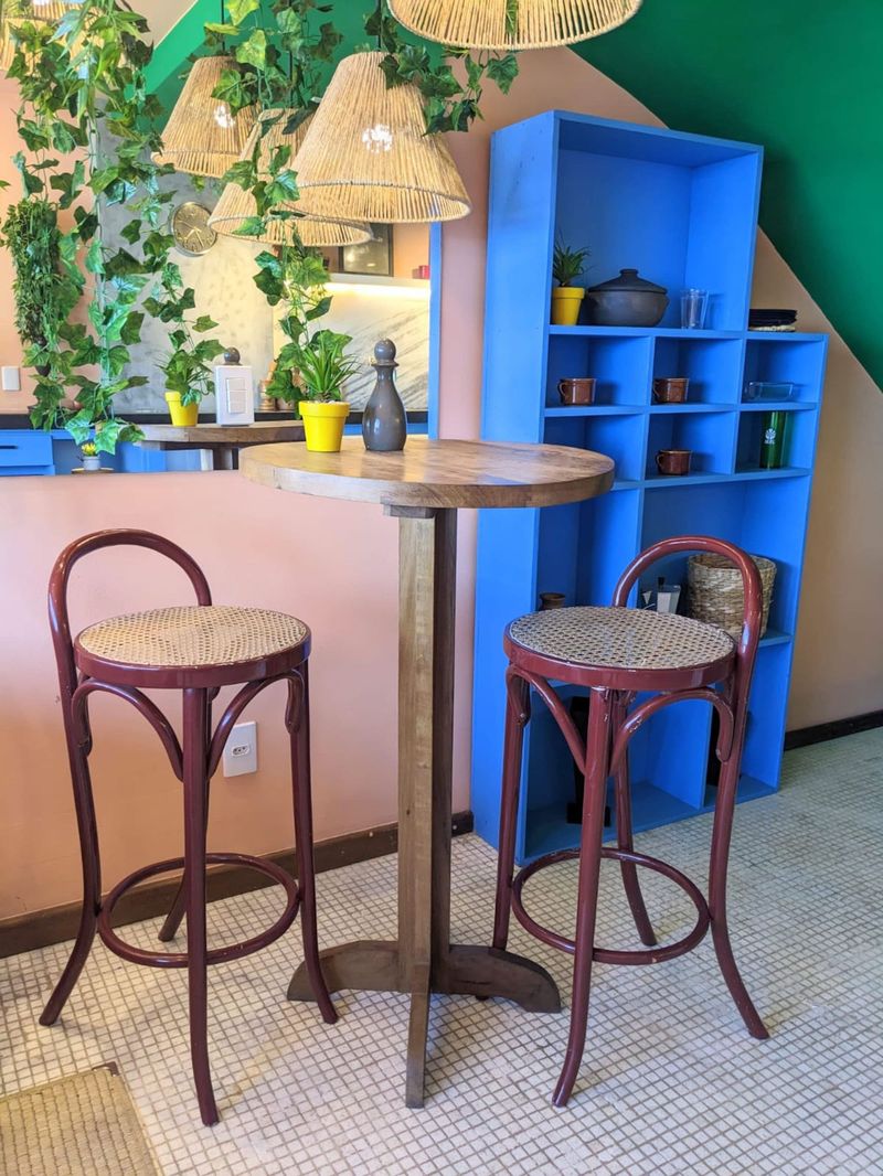Two bar stools and a high table beside blue shelving