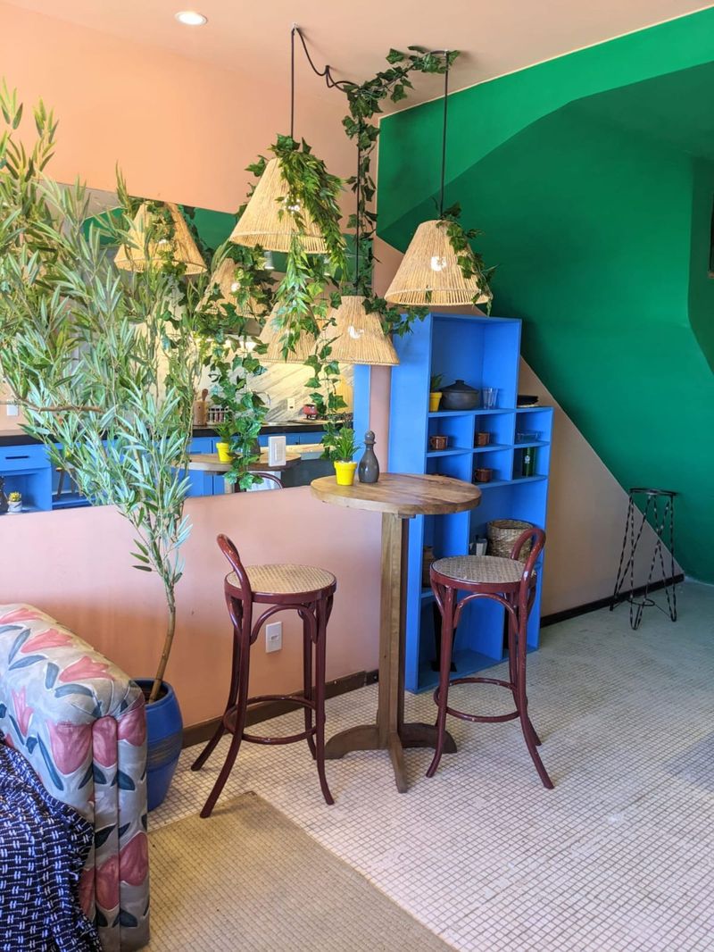 A high table and stools by the stairs, under a green wall