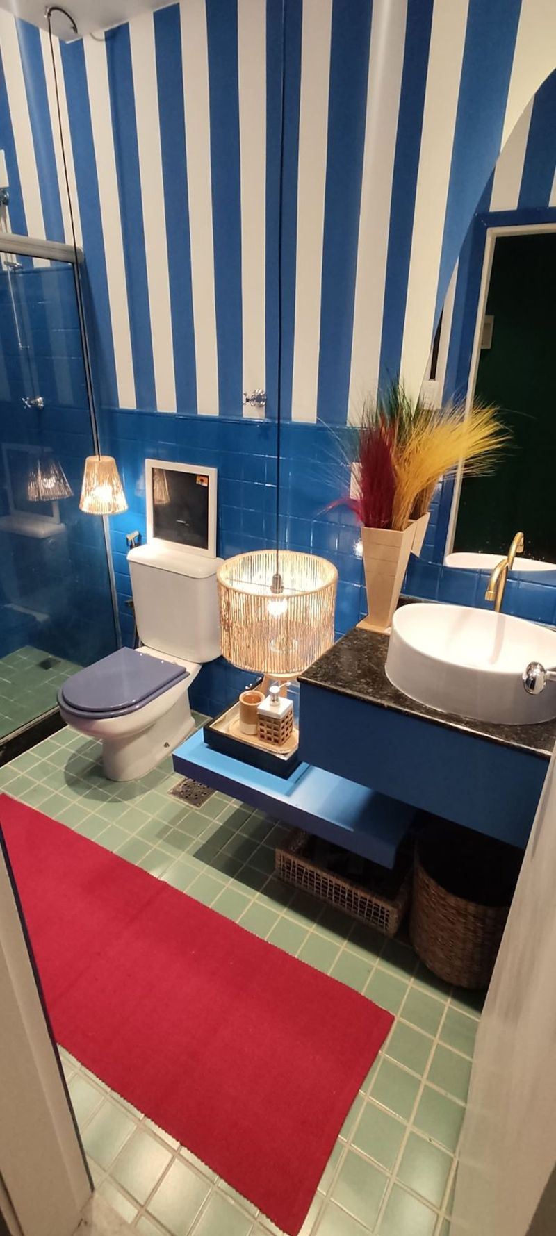 The bathroom: blue-and-white striped wall, blue vanity and a red rug
