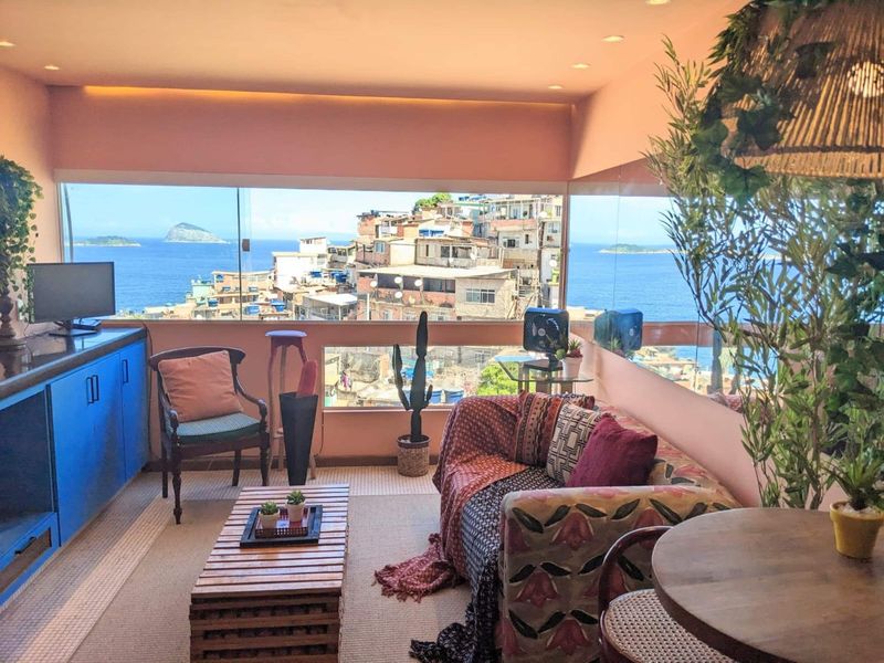 The living room: blue cabinets, a sofa, a crate coffee table and a window over the houses and the sea