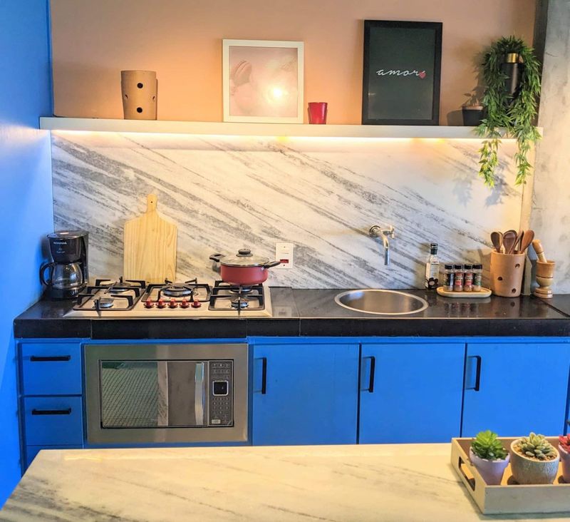Kitchen counter with a marble backsplash, gas hob, sink and built-in microwave