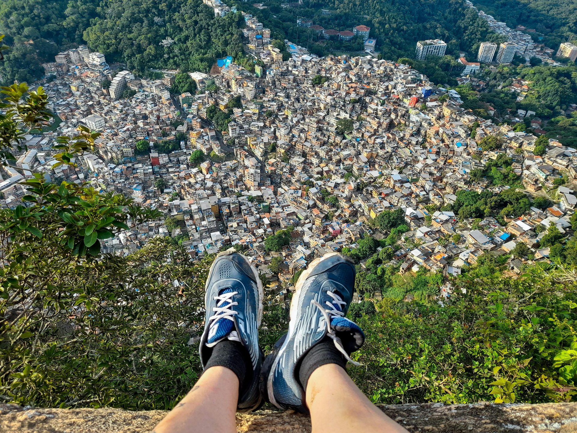 Hiker's view from the top of Dois Irmãos, feet dangling over Vidigal