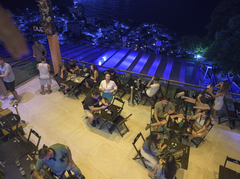 People at tables on a restaurant terrace overlooking Vidigal at night