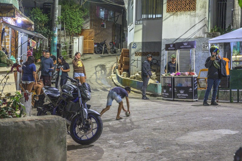 A street in Vidigal with market stalls, a motorbike and people walking